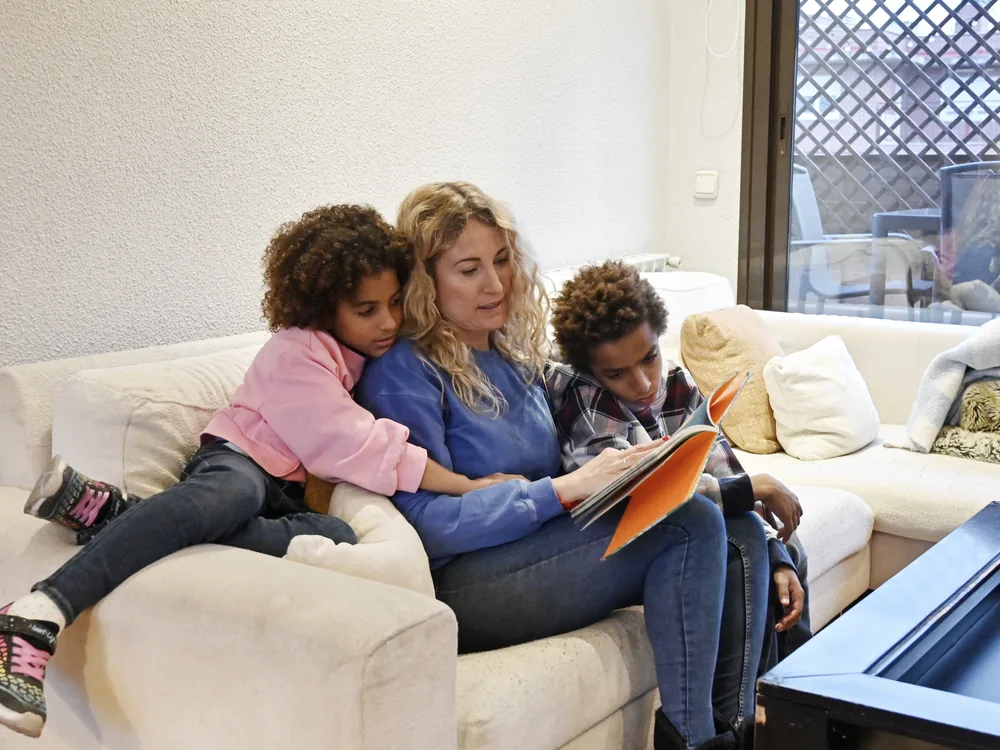 A parent reading a book aloud to two young children at home